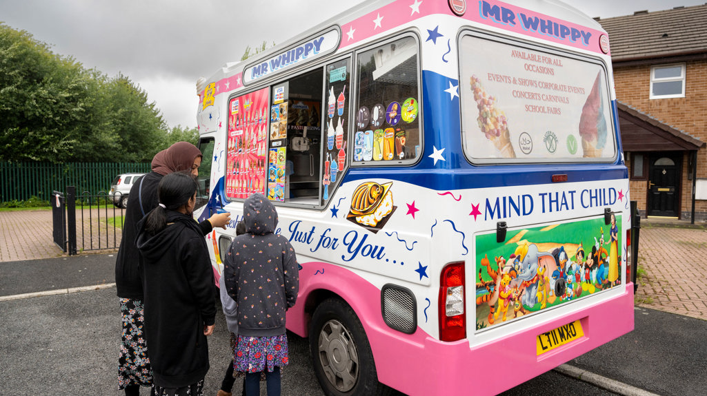 Mr Whippy ice cream van with children and families standing just outside of it