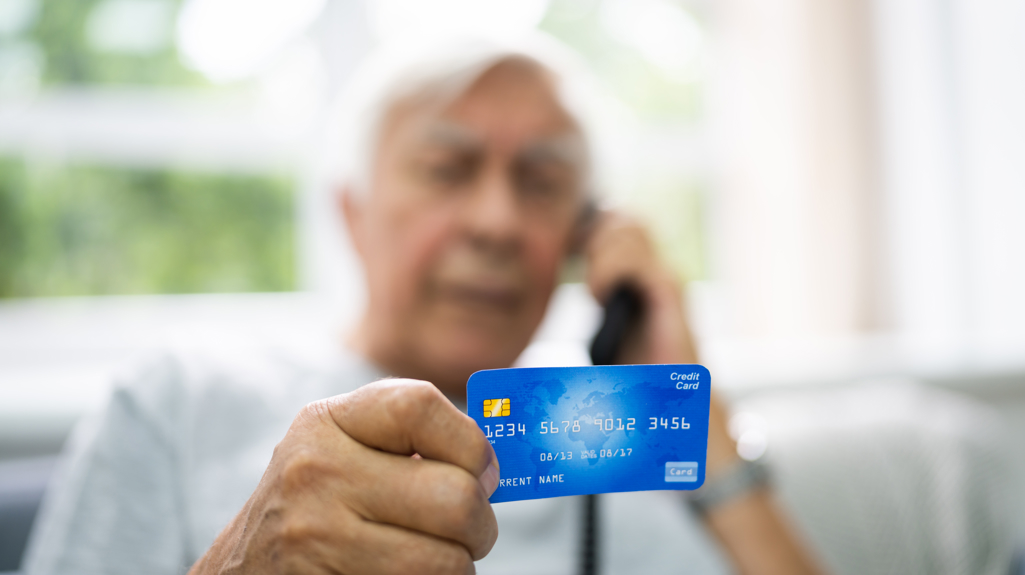 Elderly man on the telephone and holding a credit card in his hand