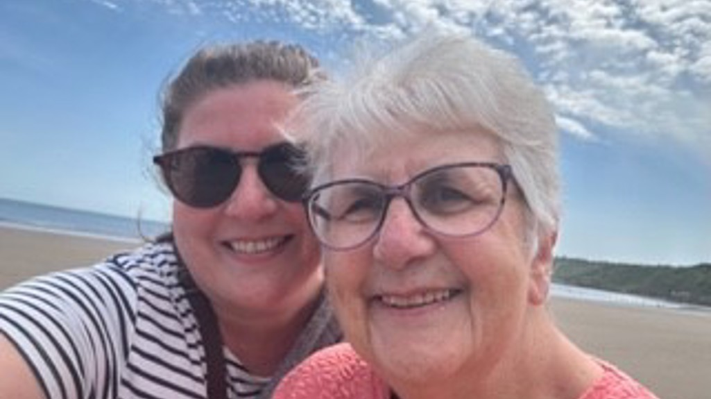 Two women taking selfie on beach smiling at camera