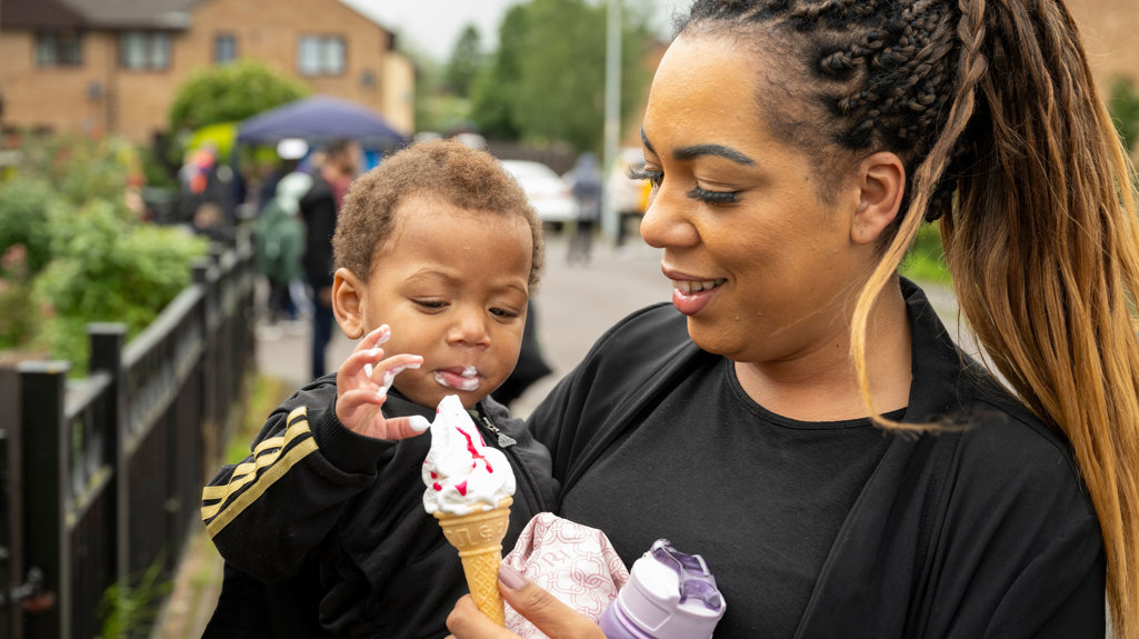 Mum and son smiling and enjoying an ice cream while stood outside. 