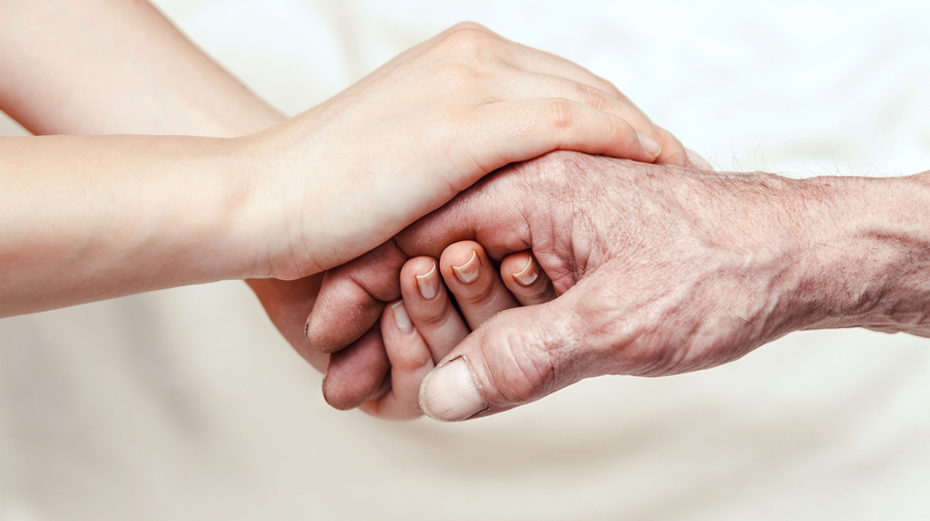 Photograph of two hands holding each other on a white background