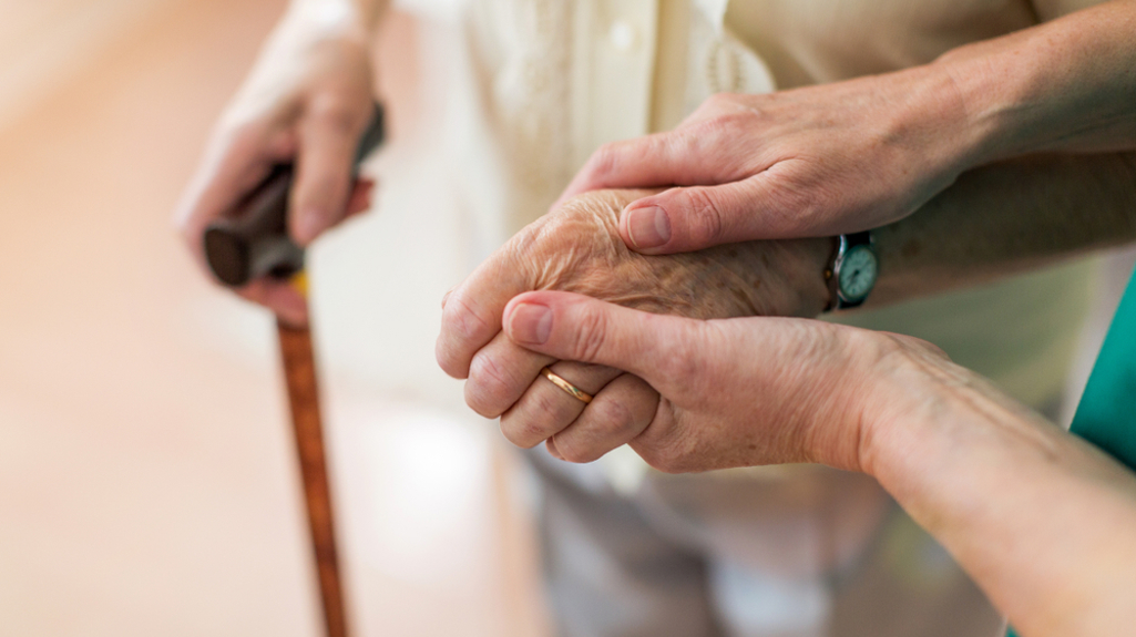 Picture of someone holding a pensioners hand whilst they walk together