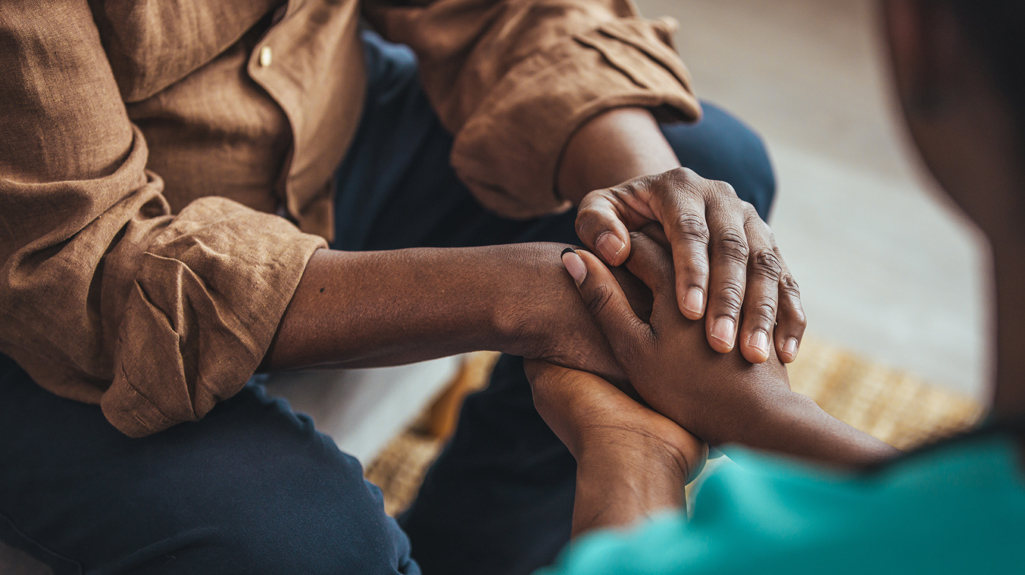 Two people holding hands in a gesture of care and support