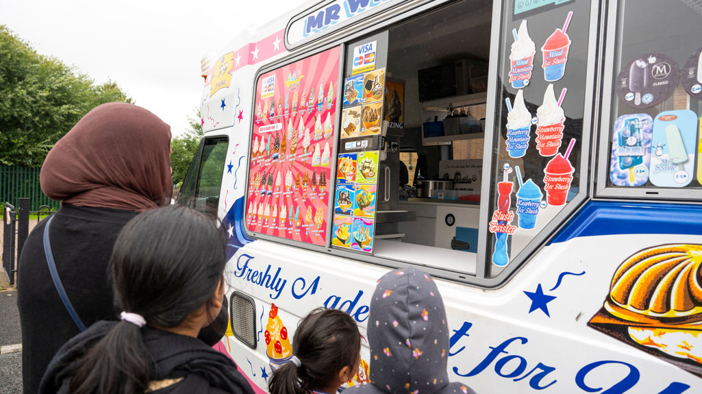 Mr Whippy ice cream van with children and families standing just outside of it