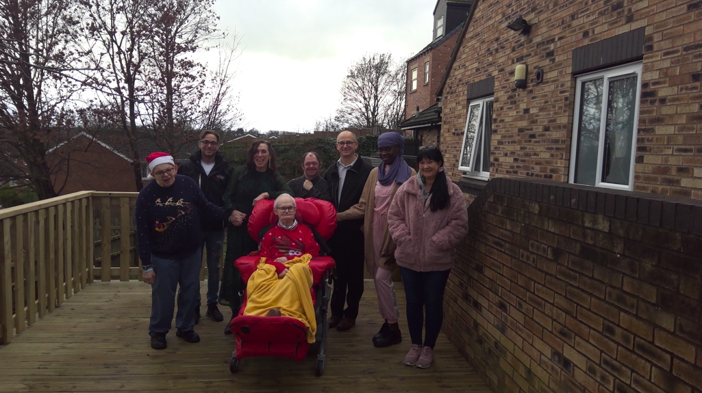 Group of people on outside decking area looking at camera and smiling