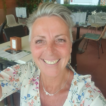 Picture of Jackie giving a big smile to the camera wearing a cream top with blue, orange and pink flowers