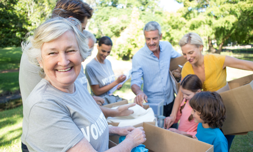 A photo of a group of people with some cardboard boxes. The people are a mix of ages. 